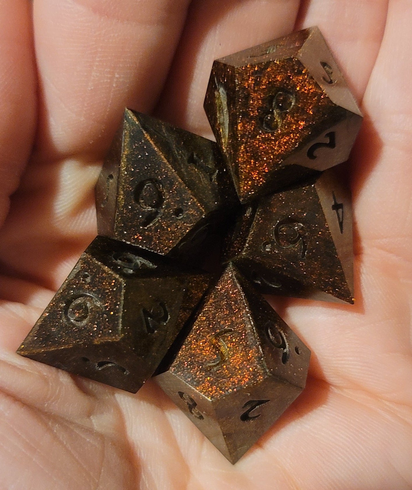Hand holding ten-sided dice with rust-like textures